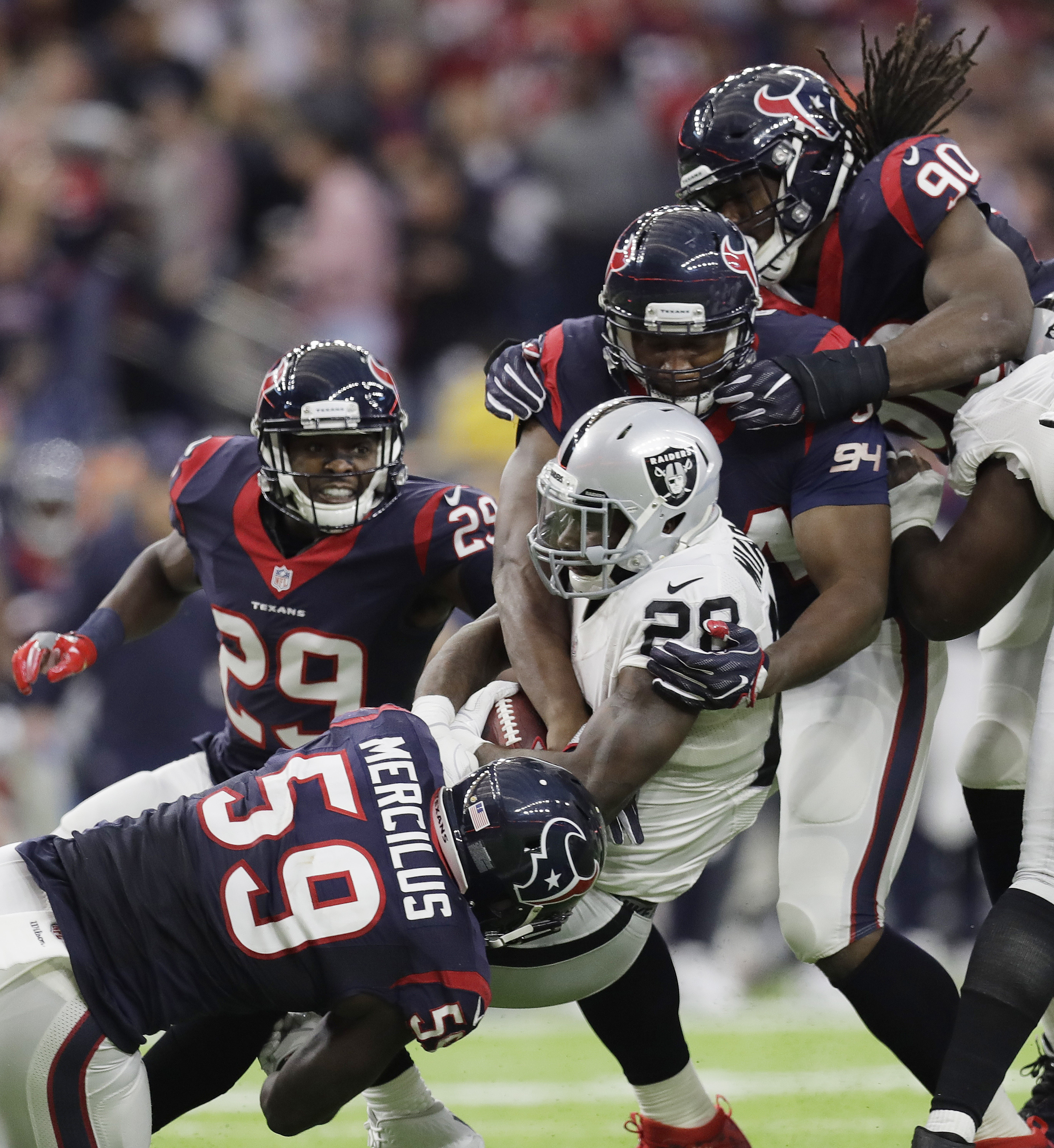 Oakland Raiders running back Latavius Murray (28) is hit by Houston Texans outside linebacker Whitney Mercilus (59) and Houston Texans defensive end Antonio Smith (94) during the second half of an AFC Wild Card NFL game Saturday, Jan. 7, 2017, in Houston. (AP Photo/Eric Gay)